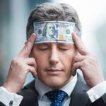 confident businessman with dollar bill on head