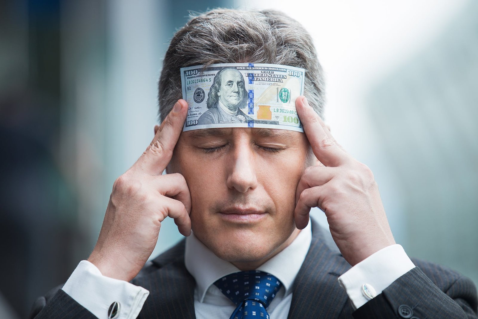 confident businessman with dollar bill on head