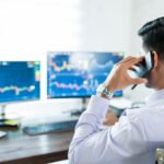 young male stock broker using computer for buying shares